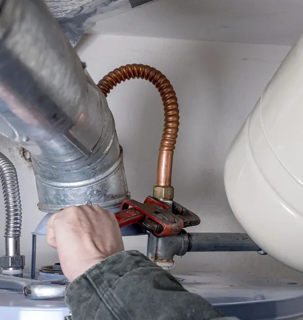 Man works on water heater with wrench