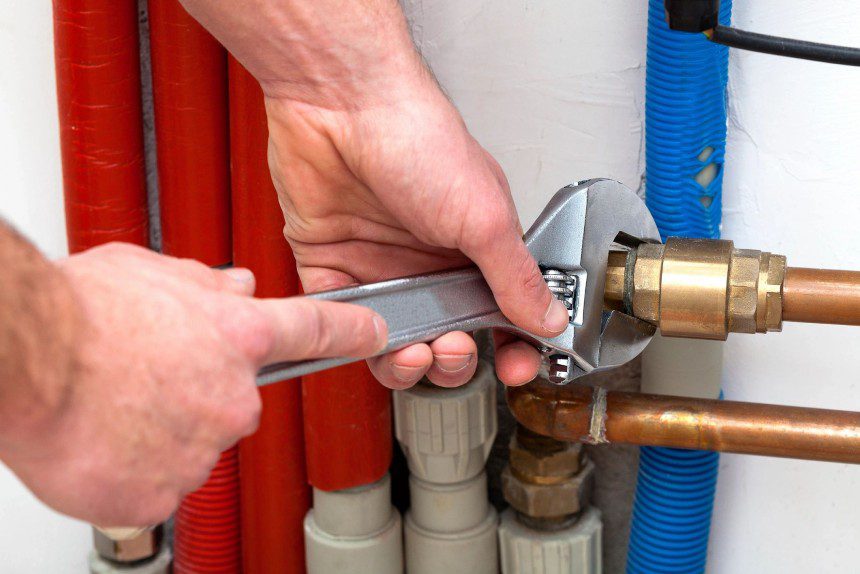 Man's hands with wrench turning off valves